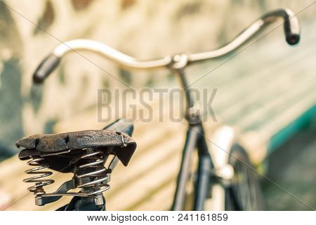 An Old Bicycle Seat With A Spring Shock Absorber. Vintage Bicycle On The Stone Wall Background.