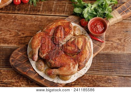 Chicken Of Tobacco On A Wooden Background With Fresh Vegetables And Tomato Sauce. Top View