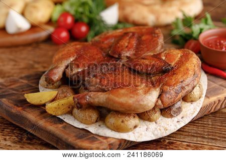 Fried Chicken On A Wooden Background With Fresh Vegetables And Potato Garnish.tsyplenok Tobacco. Rus