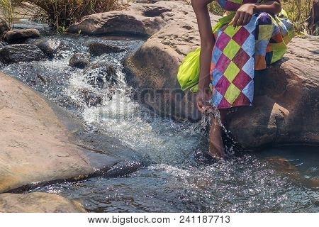 Woman In African Outfit On The Verge Of Fluent River. Interacting With Water. Angola.