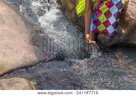 Woman In African Outfit On The Verge Of Fluent River. Interacting With Water. Angola.