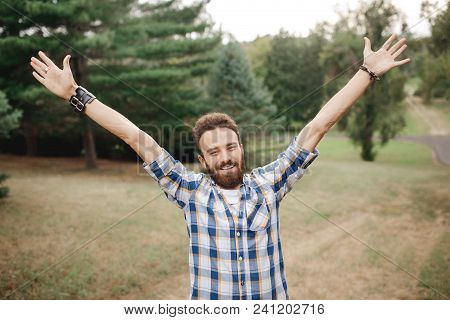 Happy Celebrating Bearded Man Posing With Hands Upin The Park