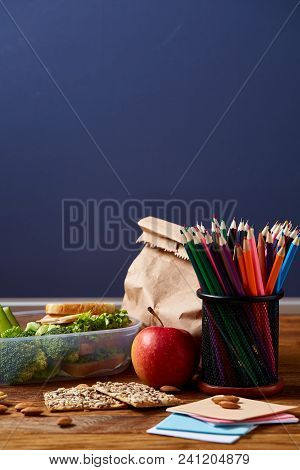 Back To School Concept, School Supplies, Assortment Of Biscuits And Transparent Lunchbox Full Of San