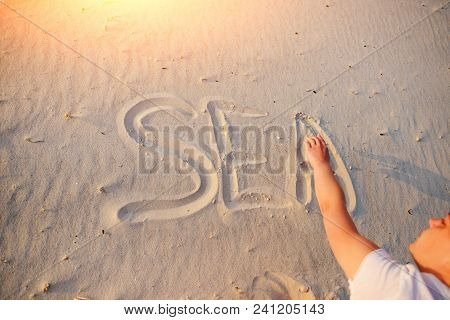 A Young Woman Writes In The Sand The Word Sea