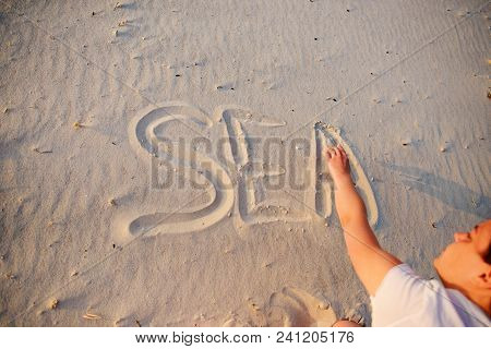 A Young Woman Writes In The Sand The Word Sea