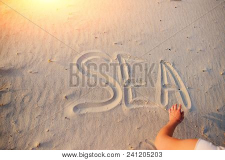 A Young Woman Writes In The Sand The Word Sea