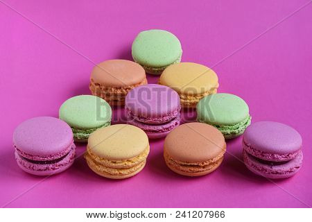 Triangle Of Multicolored Macaroons On Fucsia Background