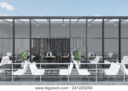 Side View Of A Glass Roof Restaurant With A Terrace. Dark Gray Walls, A Concerete Floor And Tables W