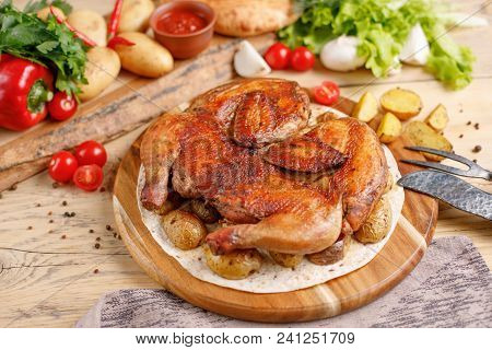 Chicken With Potato Garnish On A Wooden Background. Still Life With Textiles And Original Cutlery.