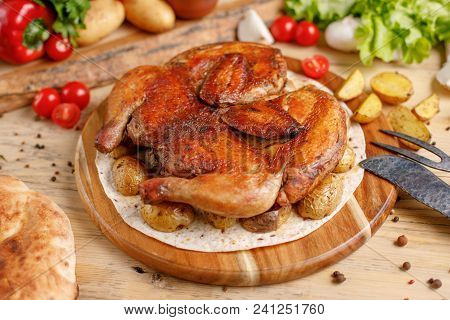 Chicken With Potato Garnish On A Round Wooden Board.appetizing Still Life And Original Cutlery.