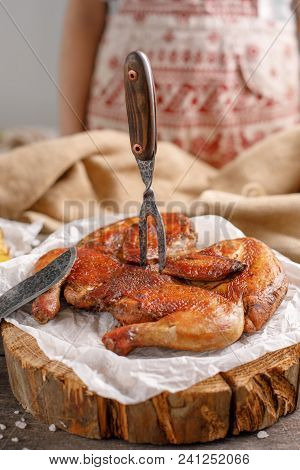 Appetizing Chicken With A Fork Stuck Into It On A Wooden Cut. Still Life With Original Cutlery And S