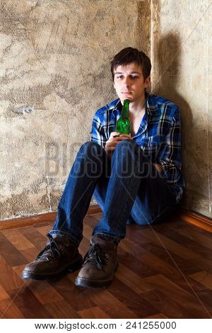 Sad Young Man With A Beer In The Corner By The Old Wall