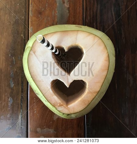 Young Coconut With Double Heart Hole And Straw On Wooden Table, Top View