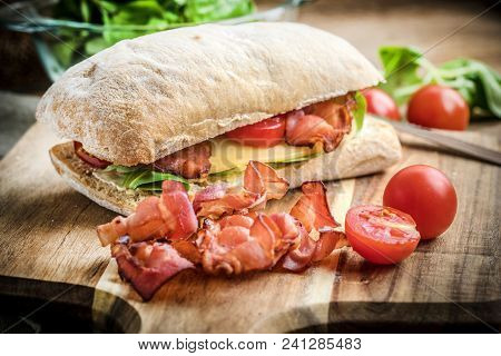Ciabatta Sandwich With Arugula Salad, Bacon And Yellow Cheese.
