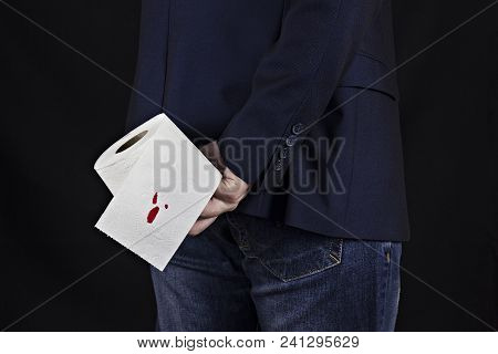 Man In Suit Holds Toilet Paper With Blood, Hemorrhoids, Black Background