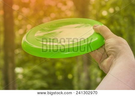 Hand Throwing A Frisbee Disc In The Park On A Summer Day With A Flash Of Frame