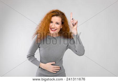 Charming Young Girl With Red Hair. A Young Girl In A Gray Sweater. Young Girl On A Gray Background.