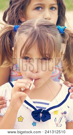Cute Sisters Enjoying Their Lollipops Outside At The Beach.