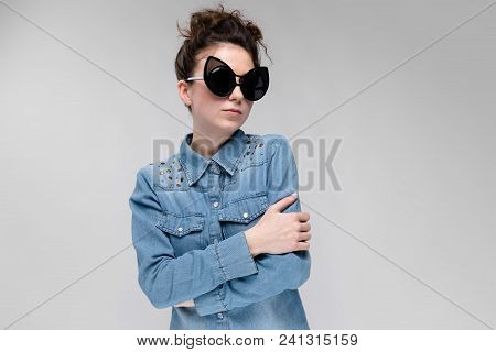 Young Girl In Black Cat Glasses On A Gray Background. Portrait Of A Young Beautiful Girl. Charming G