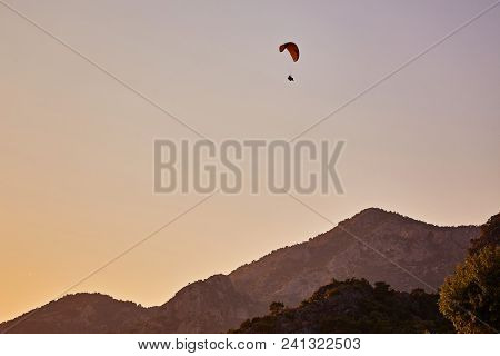 Paraglider Silhouette Flying Over Misty Mountain Valley In Beautiful Warm Sunset Colors - Sport, Act