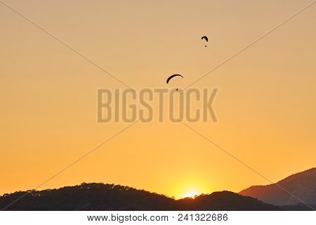 Paraglider Silhouette Flying Over Misty Mountain Valley In Beautiful Warm Sunset Colors - Sport, Act