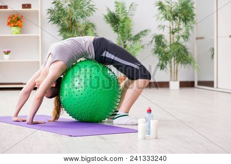 Young woman exercising with stability ball in gym