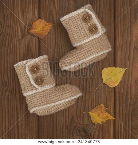 Hand Made Crochet Baby Booties On Wooden Background, Autumn Concept