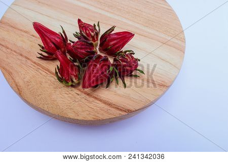Top View Of Rosella Or Hibiscus Seeds On Wood Round Cutting Board On White Background