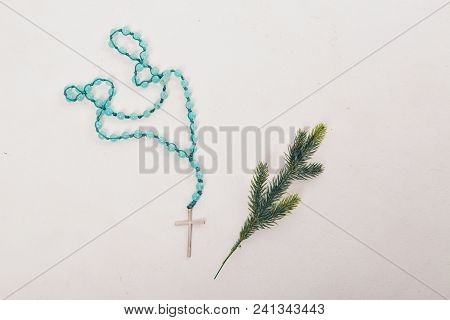 Spruce Branch And Wooden Cross On Blue Beads On White Background