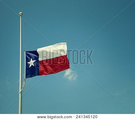 State Flag Of Texas Flying At Half-mast Or Half-staff On A Flagpole. Blue Sky Background With Copy S