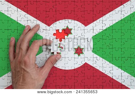 Burundi Flag  Is Depicted On A Puzzle, Which The Man's Hand Completes To Fold