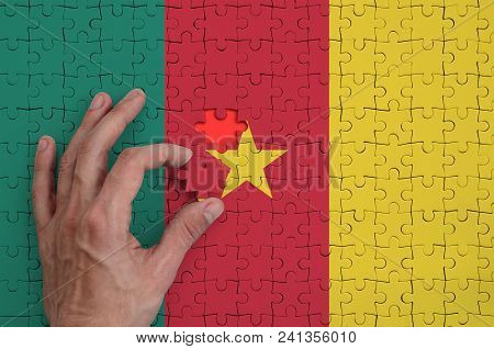 Cameroon Flag  Is Depicted On A Puzzle, Which The Man's Hand Completes To Fold