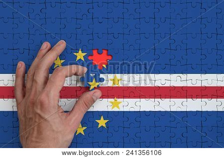 Cabo Verde Flag  Is Depicted On A Puzzle, Which The Man's Hand Completes To Fold