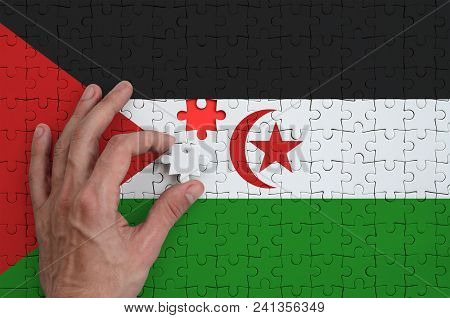 Western Sahara Flag  Is Depicted On A Puzzle, Which The Man's Hand Completes To Fold