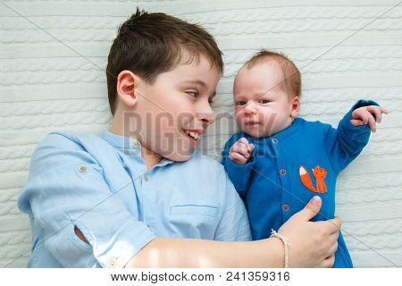 Big Brother Hugging His Newborn Baby. Toddler Kid Meeting New Sibling. Cute Boy And New Born Baby Gi