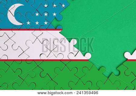 Uzbekistan Flag  Is Depicted On A Completed Jigsaw Puzzle With Free Green Copy Space On The Right Si