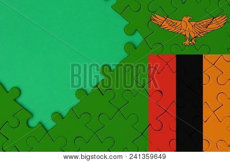 Zambia Flag  Is Depicted On A Completed Jigsaw Puzzle With Free Green Copy Space On The Left Side.