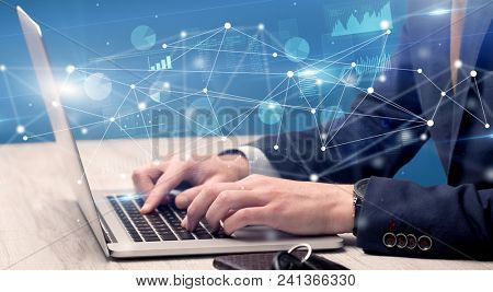 Businessman typing on laptop with linked reports charts grapghs around