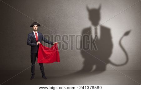 Businessman standing with red cloth in his hand and devil shadow on the background
