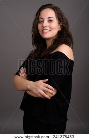 Studio Shot Of Young Happy Beautiful Woman Smiling While Wearing Black Off-shoulder Top Against Gray