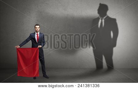 Businessman standing with red cloth on his hand and his shadow on the background