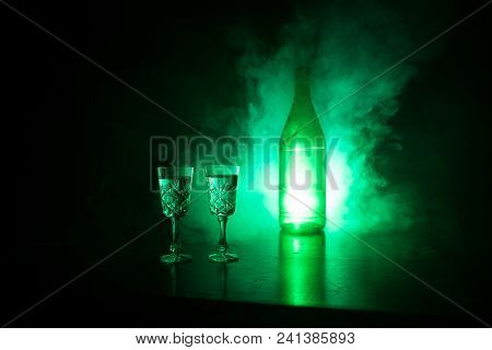 Two Glasses Of Vodka With Bottle On Dark Foggy Club Style Background With Glowing Lights (laser, Sto