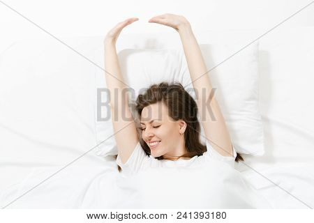 Top View Of Head Of Happy Brunette Young Woman Lying In Bed With White Sheet, Pillow, Blanket. Smili