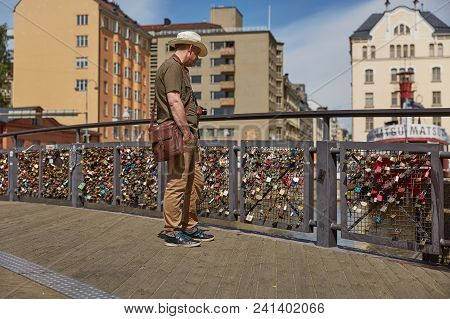 Tourist Man Observing Lovelocks Attached To A Bridge Of Love Railing In Central Helsinki, Finland