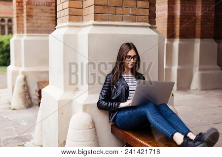 Smiling Student Girl Sitting On Bench In Park, Working With Laptop And Taking Notes, Preparing For E