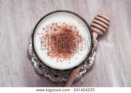 Glass Of Milk With Cinnamon Or Cocoa Powder With Honney Spoon On Rustic Background. Healthy Breakfas