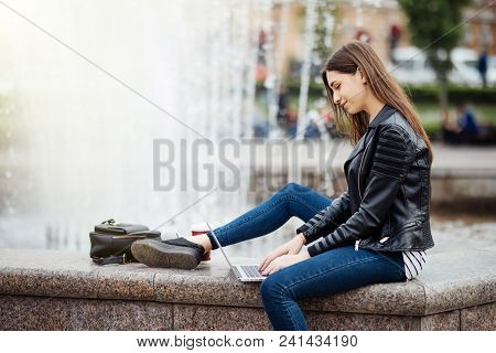 Young Woman Student Girl With Her Laptop Sitting On The Fontain