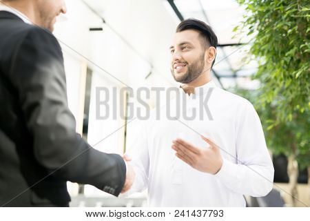 Handshake of two successful young business partners after negotiation and signing contract