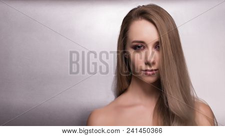 Beautiful Young Girl With Bright Pink Make-up And Combed Hair On A Gray Background Looks Into The Fr
