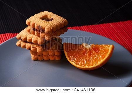 Chocolate Chip Cookies And Orange On Gray Plate And On Red With Black Table